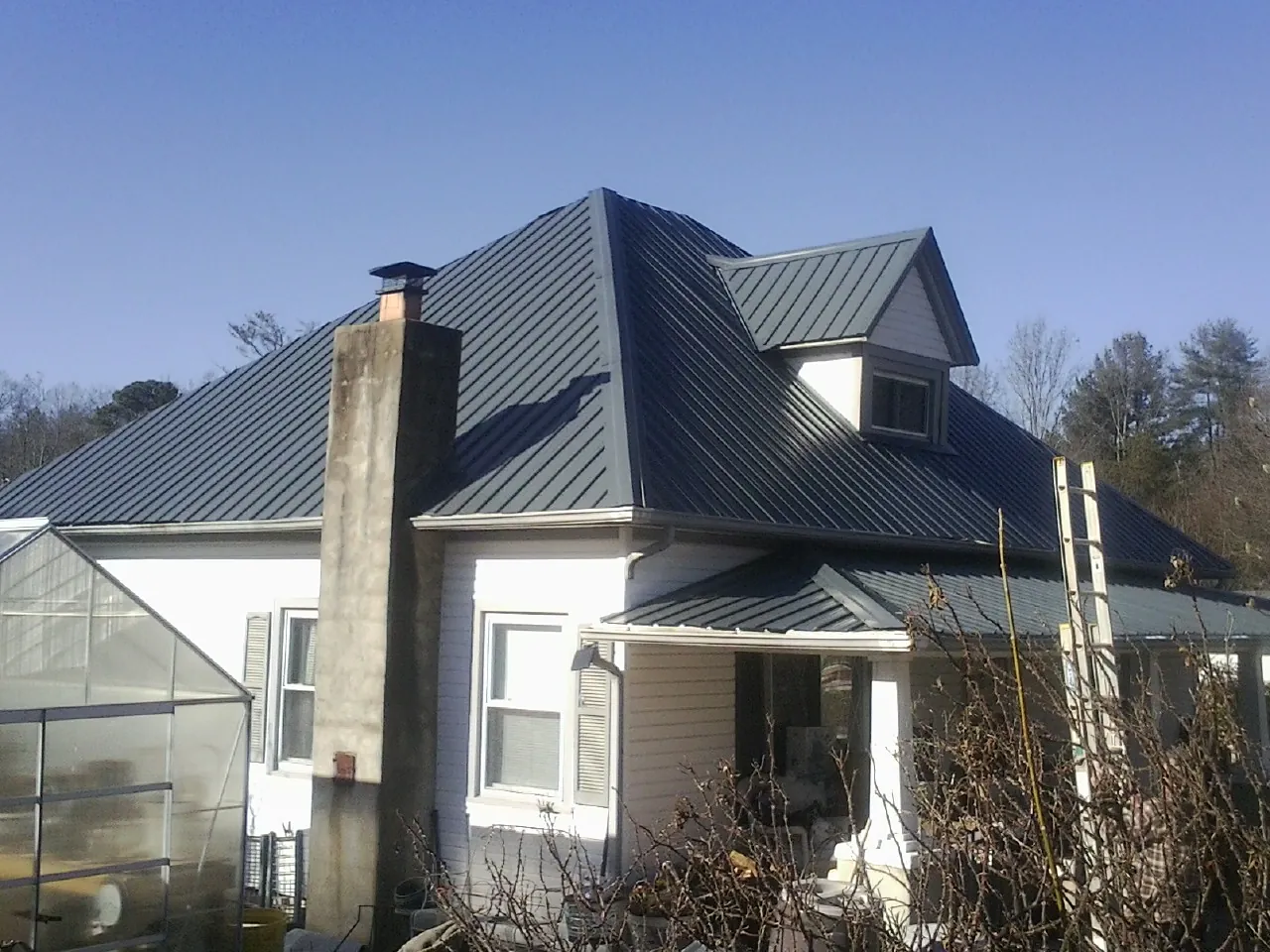 Dark blue standing seam metal roof on a white farmhouse with dormer — Slate & Tile Roof Repair by Roofing Brothers in Olivebridge