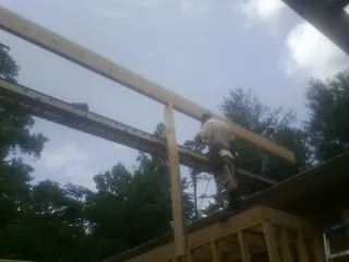 Carpenter setting a ridge beam over a new addition frame in Olivebridge