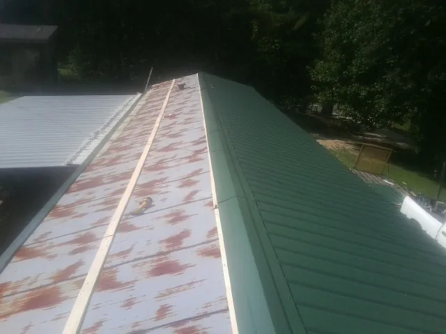 Old rusted panels beside newly installed green metal roofing — Wind Damage Roof Repair by Roofing Brothers in Olivebridge