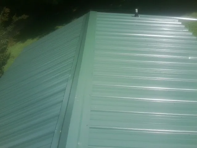New green metal panels meeting at the ridge of a roof — Flat Roof Repair work by our crew in Olivebridge