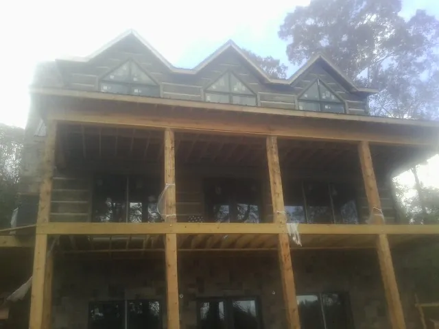Dormers and porch framing on a large log home under construction — Roof Coating work by our crew in Olivebridge