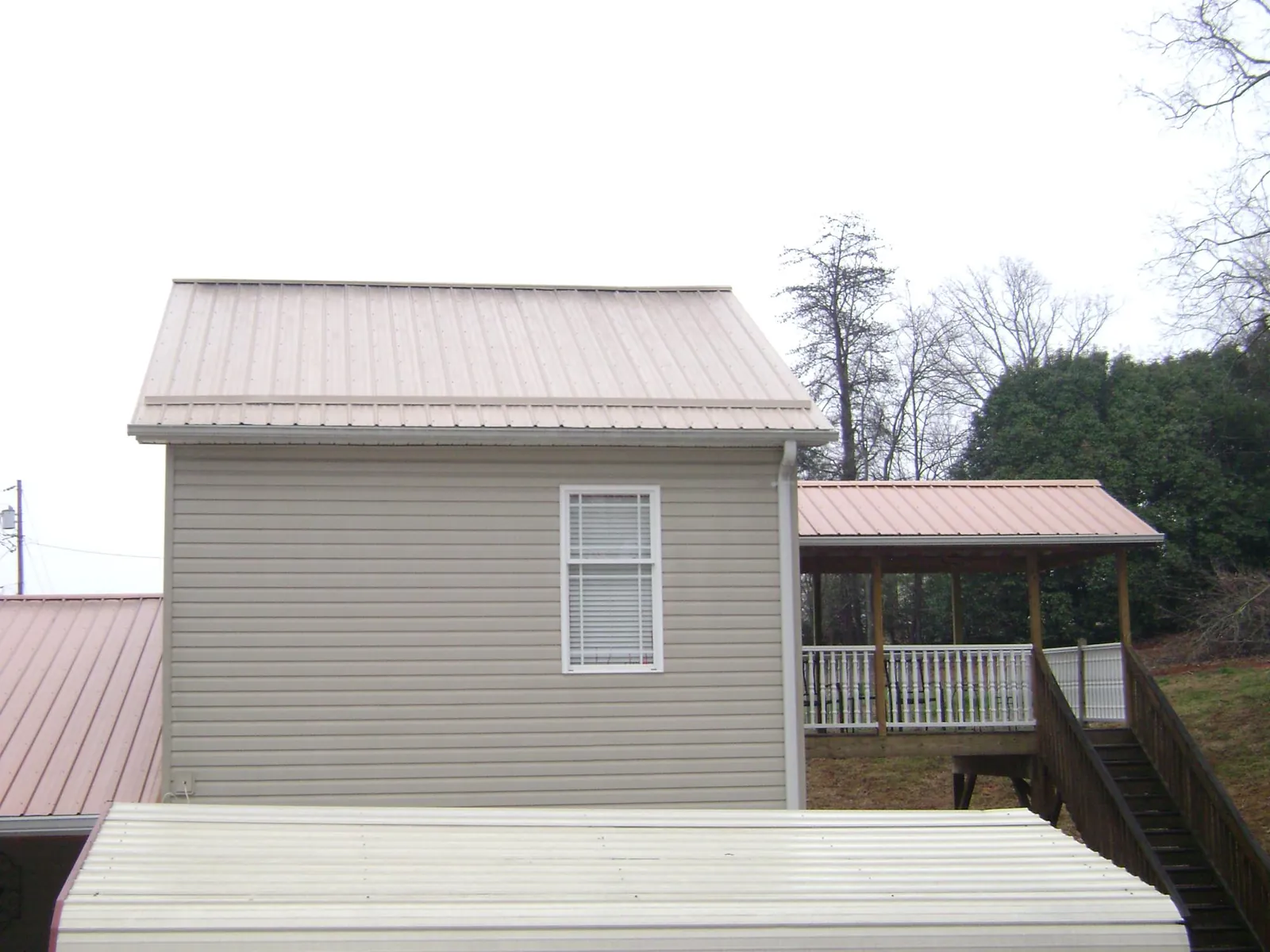 Tan metal roofs on a two story addition and attached porch, from a Roof Replacement job in Olivebridge