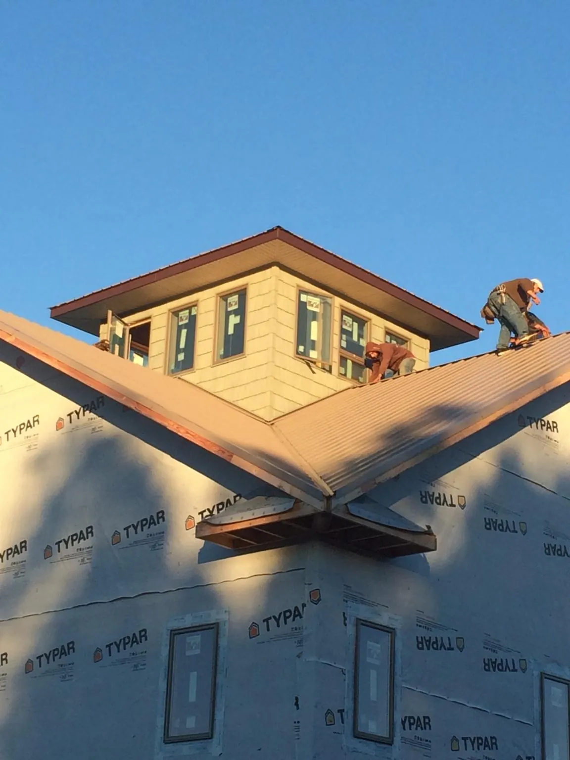 Roofers working around a rooftop cupola on a new metal roof at sunset — Roof Waterproofing in Olivebridge by Roofing Brothers